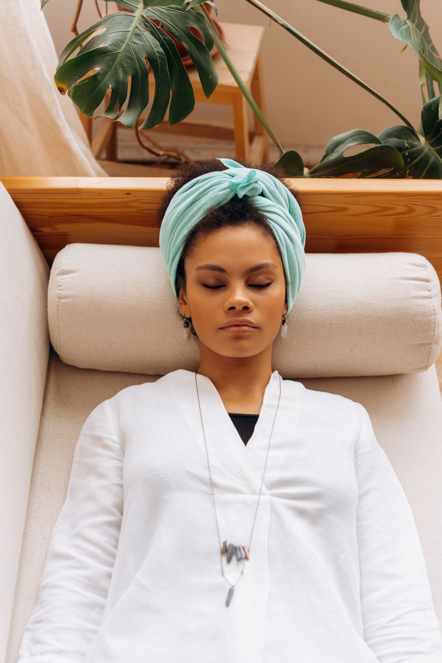A serene woman resting indoors with a headscarf and closed eyes, embodying tranquility.